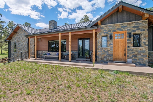 25350 Ridge Way, Golden, CO 80401 - rear view of house with stone siding, a standing seam roof, a chimney, metal roof, and a yard