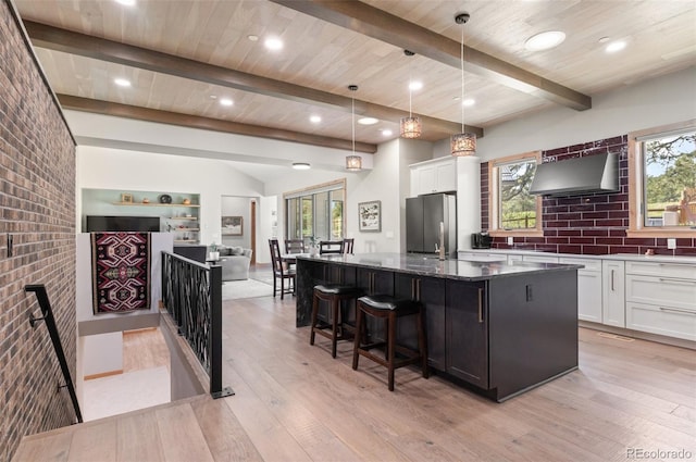 25350 Ridge Way, Golden, CO 80401 - kitchen with wall chimney range hood, freestanding refrigerator, light wood-style flooring, white cabinets, and dark stone countertops