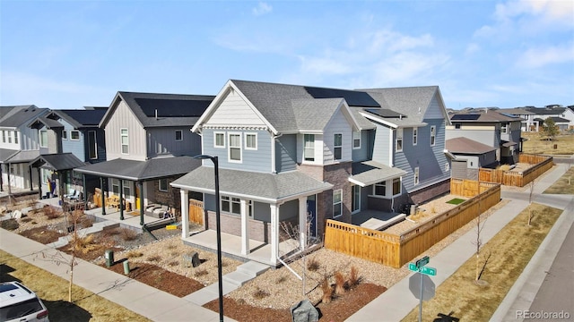 view of front facade with a residential view, roof with shingles, and fence