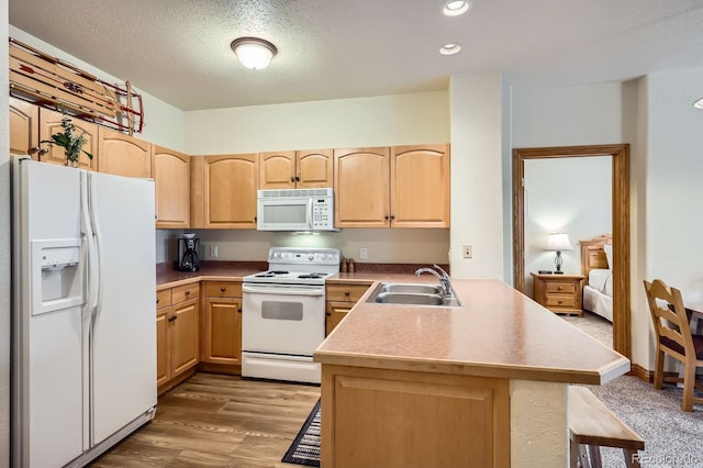 22714 US Highway 6 Unit 5945, Keystone, CO 80435 - kitchen featuring white appliances, light brown cabinetry, a peninsula, a breakfast bar area, and light wood finished floors