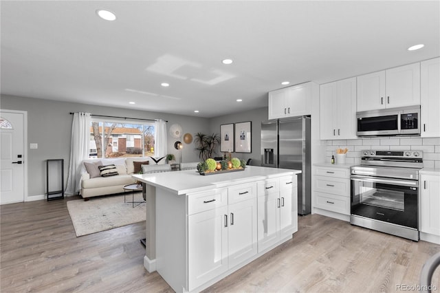 kitchen with stainless steel appliances, light hardwood / wood-style flooring, a kitchen island, and white cabinets