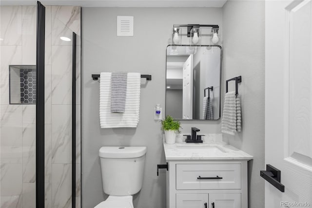 bathroom featuring vanity, an enclosed shower, and toilet