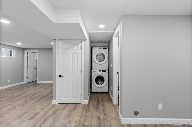 laundry room with stacked washing maching and dryer and light hardwood / wood-style floors