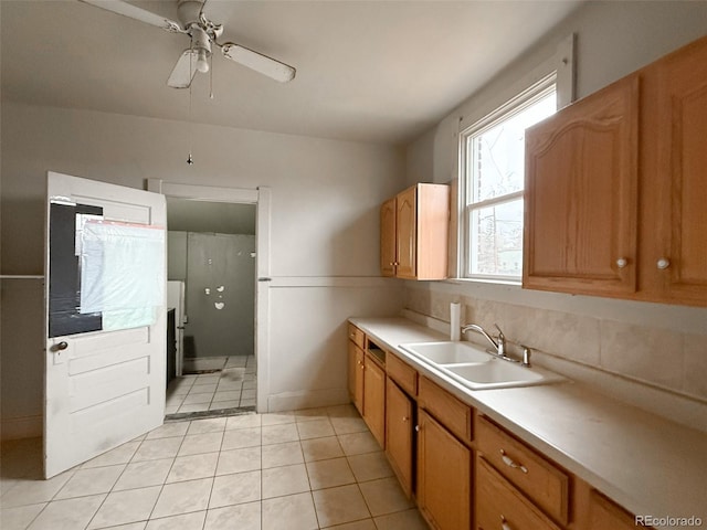 kitchen with a sink, light tile patterned flooring, light countertops, decorative backsplash, and ceiling fan