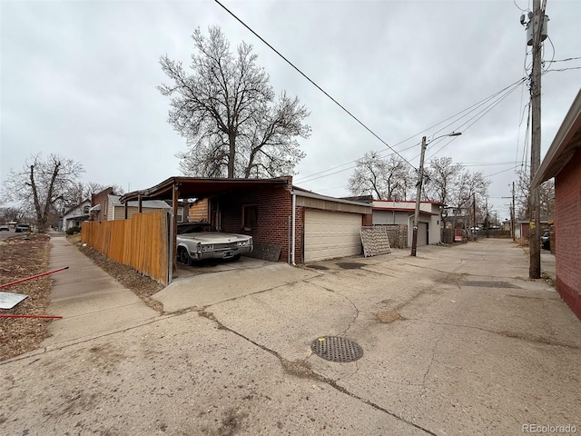 exterior space with a carport, concrete driveway, and fence