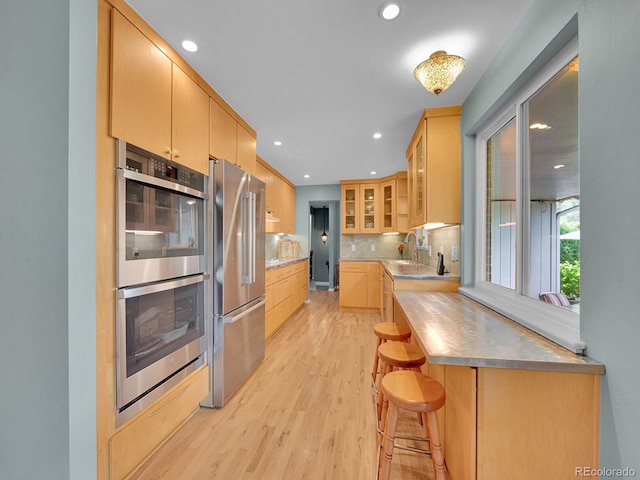 595 W Lake Ave, Littleton, CO 80120 - kitchen featuring appliances with stainless steel finishes, light wood-style flooring, glass insert cabinets, stainless steel counters, and backsplash