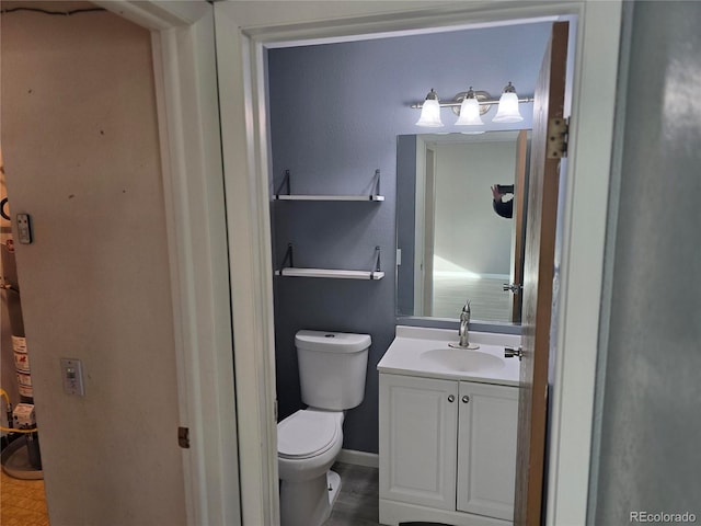 bathroom featuring baseboards, toilet, and vanity