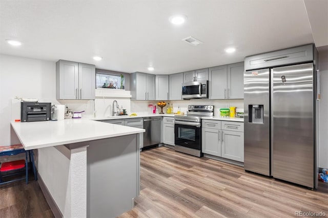 1112-11121/2 Krameria St, Denver, CO 80220 - kitchen with stainless steel appliances, gray cabinetry, a peninsula, light wood-type flooring, and recessed lighting