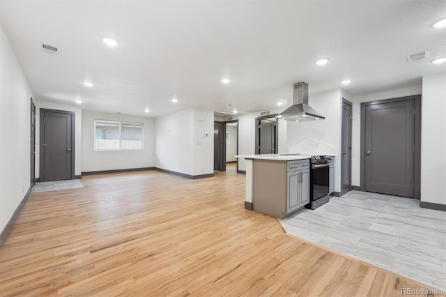 1112-11121/2 Krameria St, Denver, CO 80220 - kitchen with island exhaust hood, stainless steel range with electric cooktop, light wood finished floors, a peninsula, and recessed lighting