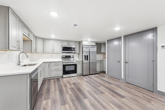 1112-11121/2 Krameria St, Denver, CO 80220 - kitchen with appliances with stainless steel finishes, gray cabinetry, light wood-style flooring, light countertops, and recessed lighting