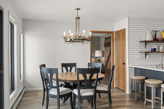 369 County Road 4051, Granby, CO 80446 - dining space featuring a baseboard heating unit, wood finished floors, a chandelier, baseboards, and a barn door