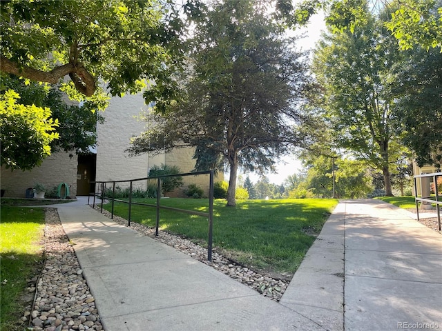 view of property's community featuring a lawn and fence