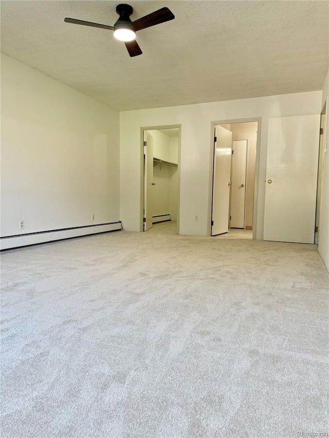 unfurnished bedroom with baseboard heating, a textured ceiling, and light colored carpet