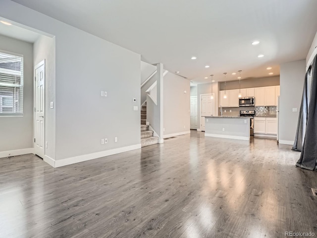 4773 Kittredge St, Denver, CO 80239 - unfurnished living room featuring recessed lighting, stairs, baseboards, and wood finished floors
