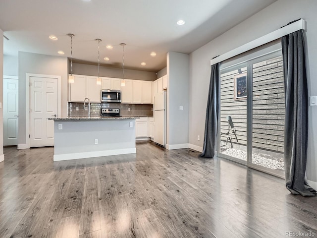 4773 Kittredge St, Denver, CO 80239 - kitchen featuring stainless steel appliances, white cabinetry, tasteful backsplash, wood finished floors, and recessed lighting