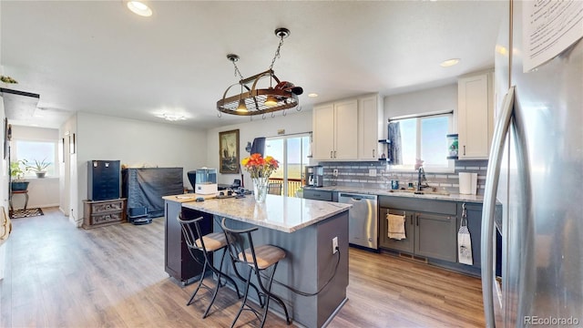 40291 Gold Nugget Dr, Deer Trail, CO 80105 - kitchen featuring appliances with stainless steel finishes, a kitchen island, a breakfast bar area, backsplash, and light wood finished floors
