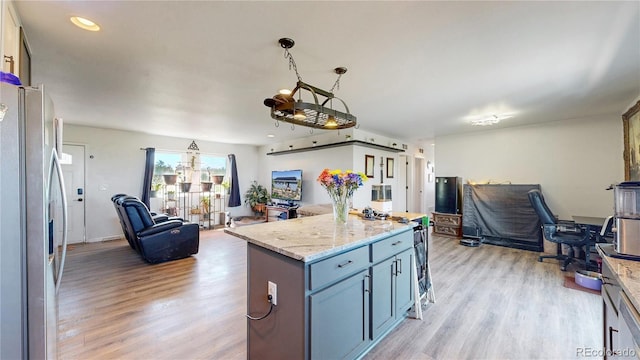 40291 Gold Nugget Dr, Deer Trail, CO 80105 - kitchen featuring stainless steel fridge with ice dispenser, open floor plan, light wood-style floors, light stone countertops, and a center island