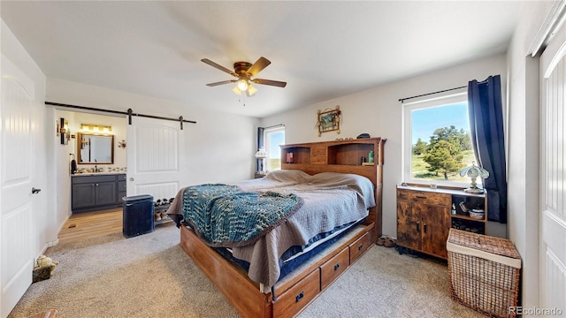 40291 Gold Nugget Dr, Deer Trail, CO 80105 - bedroom featuring light carpet, a barn door, connected bathroom, and a ceiling fan