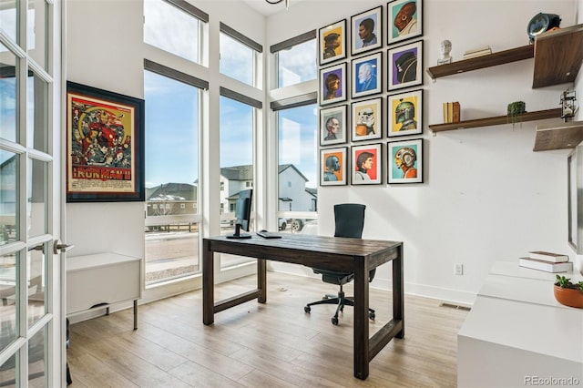 home office featuring light wood-type flooring, baseboards, and visible vents