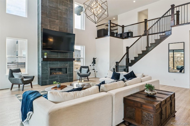 living area featuring stairway, a fireplace, a high ceiling, and wood finished floors