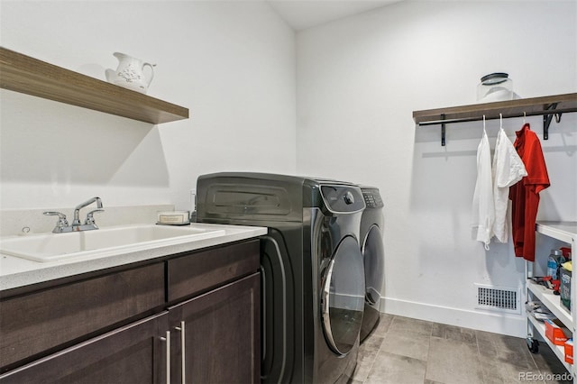 laundry room featuring baseboards, visible vents, washing machine and clothes dryer, cabinet space, and a sink