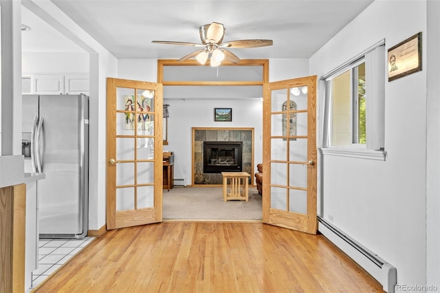 1732 Lansing St, Aurora, CO 80010 - unfurnished living room with a baseboard heating unit, light wood-type flooring, a ceiling fan, a tiled fireplace, and baseboard heating
