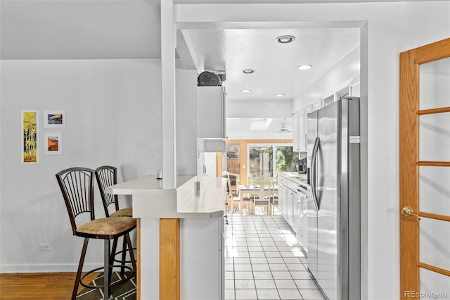 1732 Lansing St, Aurora, CO 80010 - kitchen with stainless steel fridge with ice dispenser, a kitchen bar, a peninsula, white cabinetry, and recessed lighting