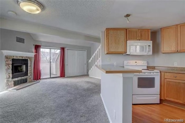 kitchen with white appliances, visible vents, a fireplace, light carpet, and open floor plan