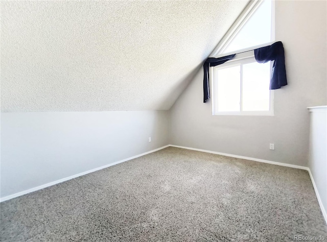 bonus room with carpet flooring, a textured ceiling, baseboards, and vaulted ceiling