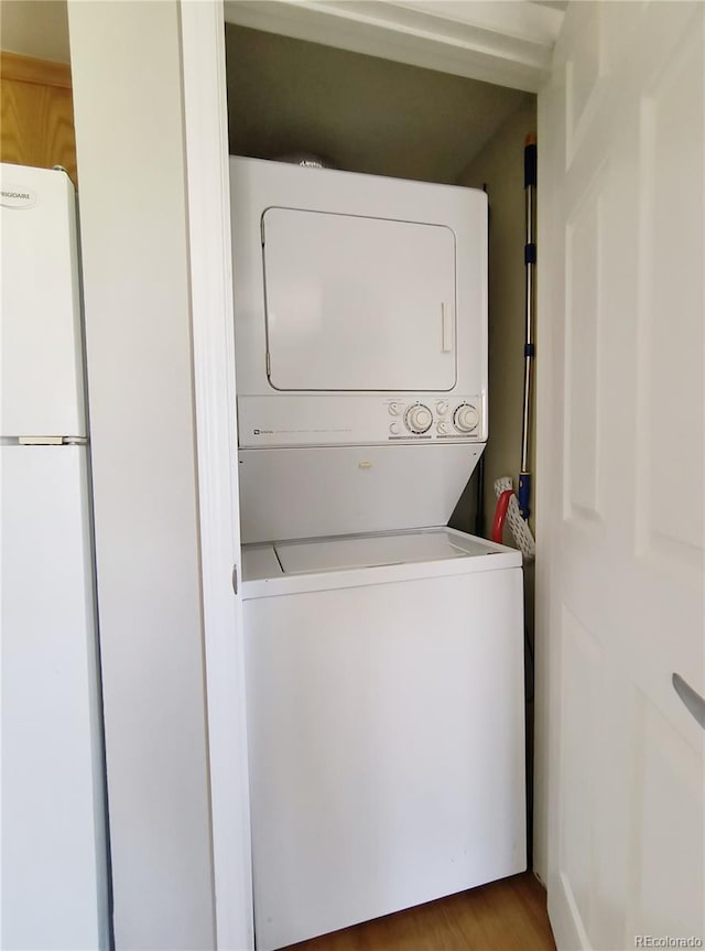 laundry area with laundry area, stacked washer / drying machine, and wood finished floors