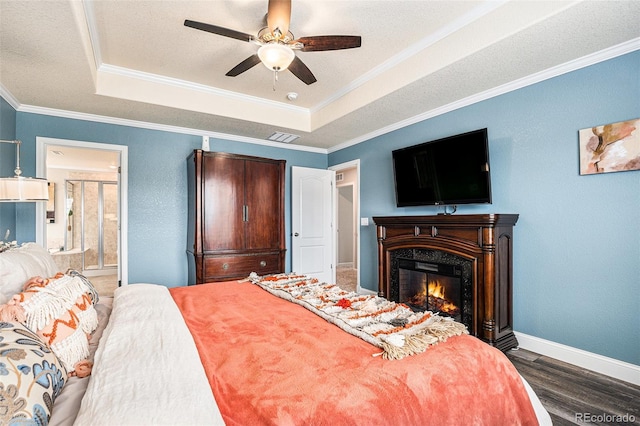 13326 Olive Way, Thornton, CO 80602 - bedroom with a raised ceiling, wood finished floors, baseboards, ornamental molding, and a glass covered fireplace