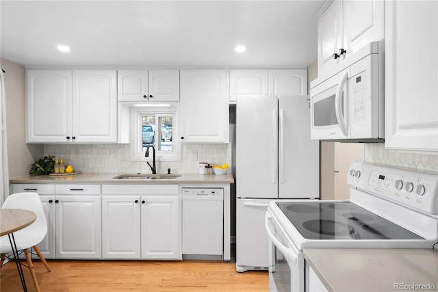 kitchen featuring white cabinets, white appliances, light hardwood / wood-style floors, and sink