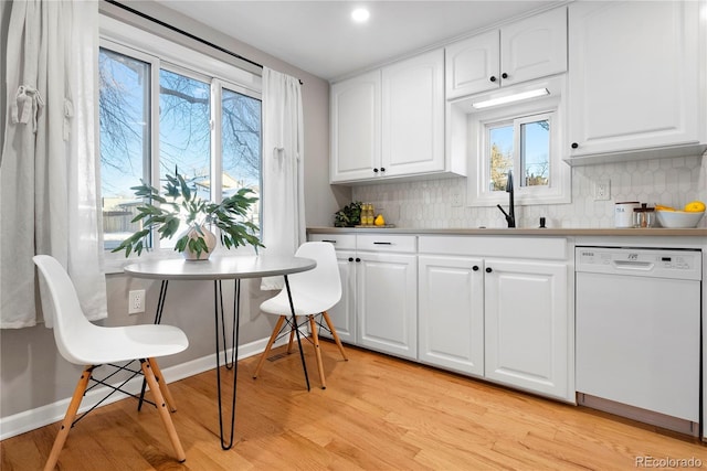 kitchen featuring white dishwasher, sink, light hardwood / wood-style flooring, tasteful backsplash, and white cabinetry