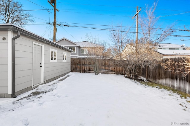 snowy yard with a fenced backyard