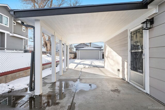 snow covered patio featuring a garage and an outdoor structure