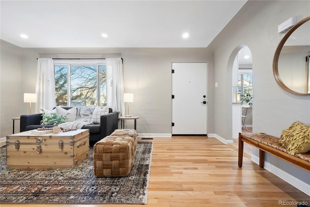 foyer entrance featuring a wealth of natural light, light wood-type flooring, arched walkways, and baseboards