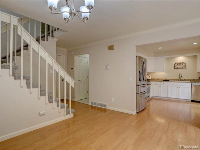 11867 Elk Head Range Rd, Littleton, CO 80127 - unfurnished living room with light wood-style flooring, stairway, ornamental molding, a chandelier, and recessed lighting