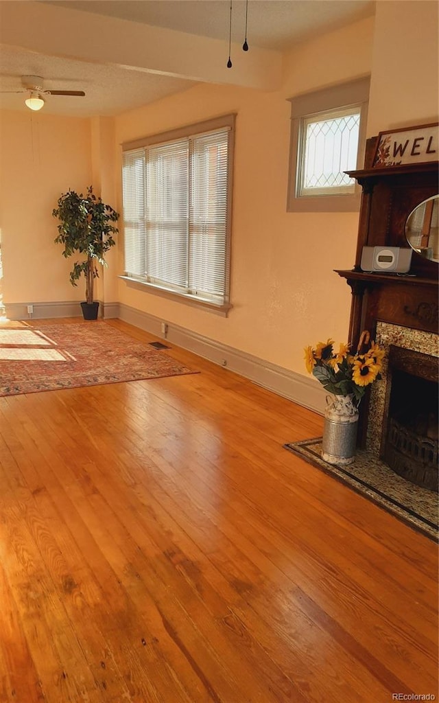 living room with ceiling fan, baseboards, hardwood / wood-style floors, and a fireplace