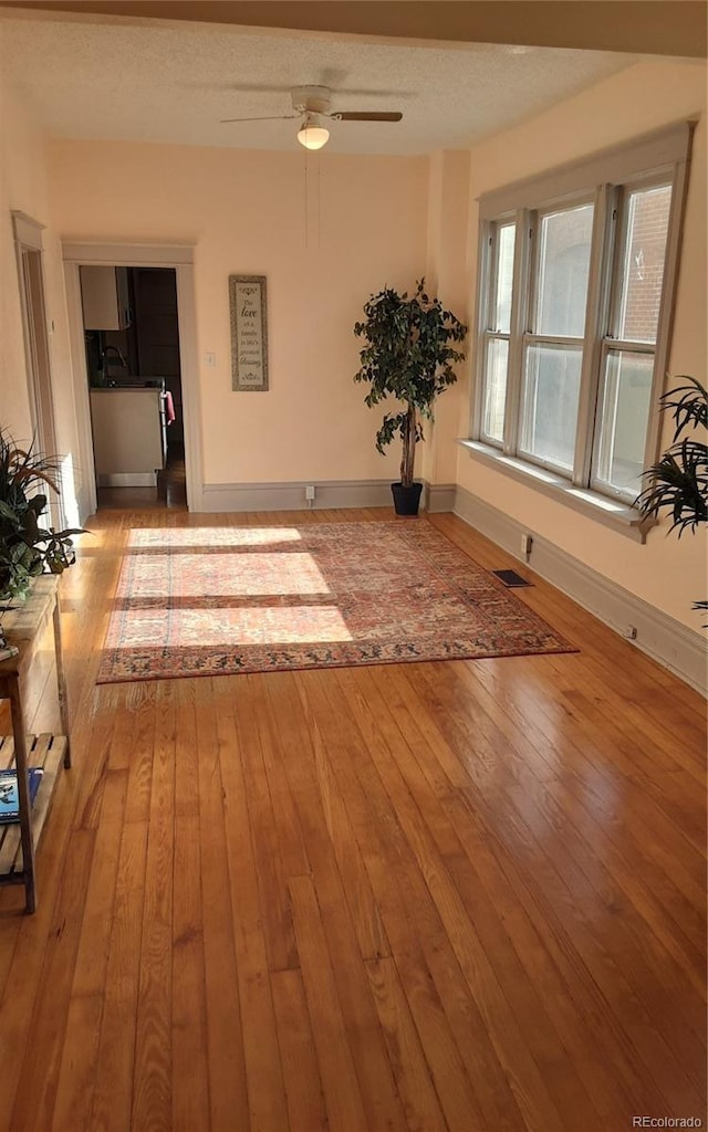 interior space featuring visible vents, baseboards, a ceiling fan, and hardwood / wood-style flooring