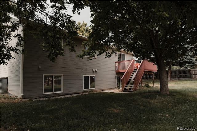 back of property with a wooden deck and a lawn