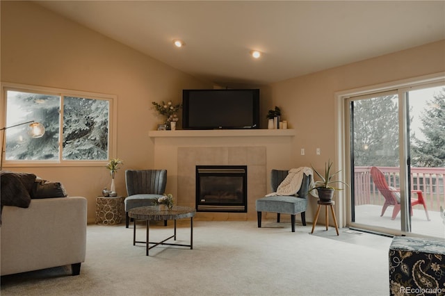 carpeted living room featuring vaulted ceiling and a tile fireplace