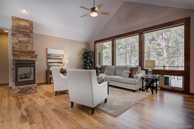 living room with a fireplace, light wood-style flooring, a ceiling fan, and a wealth of natural light