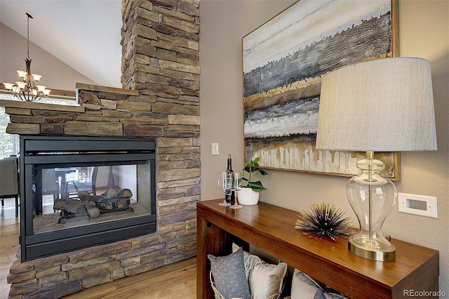 room details with a notable chandelier, a stone fireplace, and wood finished floors