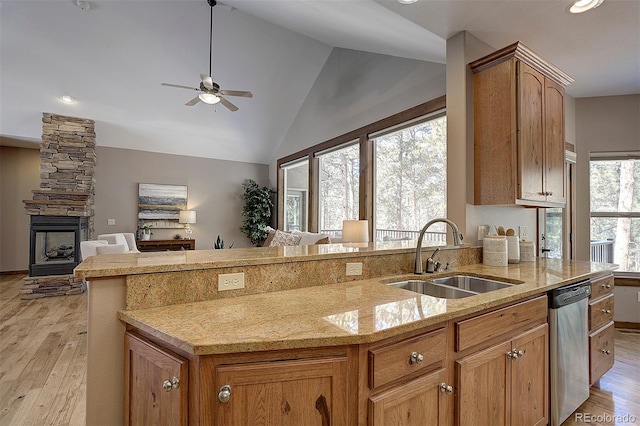 kitchen with lofted ceiling, ceiling fan, a sink, stainless steel dishwasher, and light wood-type flooring