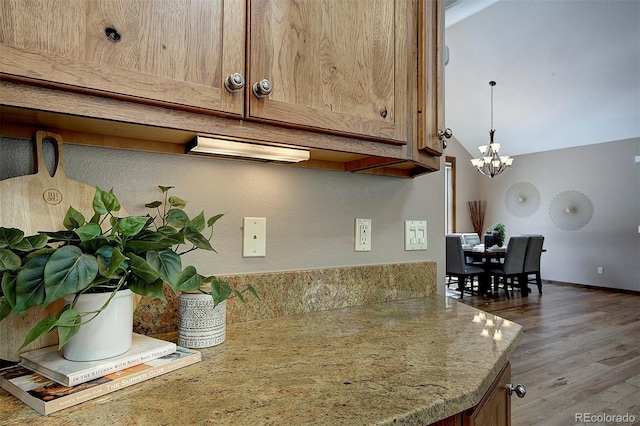 kitchen with light wood finished floors, baseboards, a chandelier, decorative light fixtures, and brown cabinetry