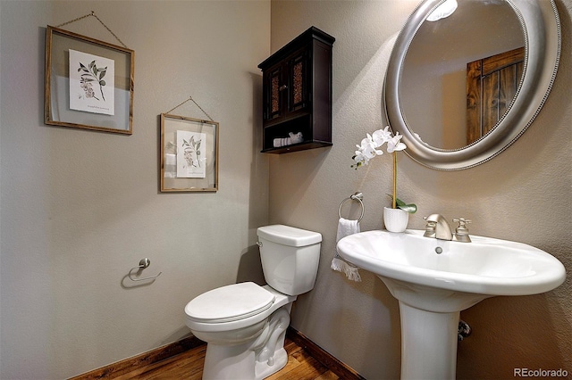 bathroom with toilet, baseboards, and wood finished floors