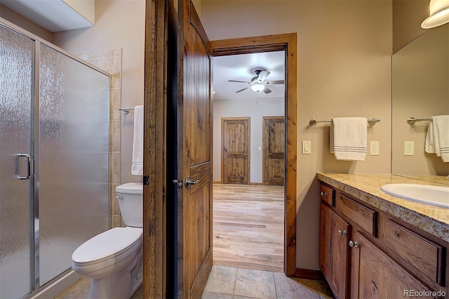 bathroom featuring vanity, toilet, a ceiling fan, and a stall shower