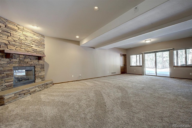 unfurnished living room featuring a stone fireplace, a healthy amount of sunlight, and baseboards