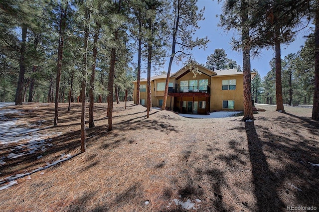 back of property featuring a balcony and stucco siding