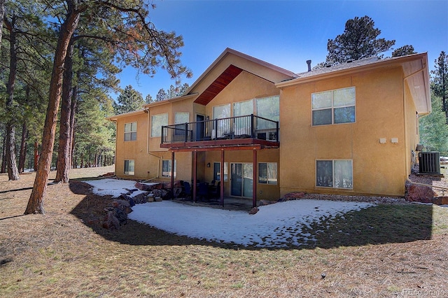 rear view of house with central air condition unit, stucco siding, and a deck